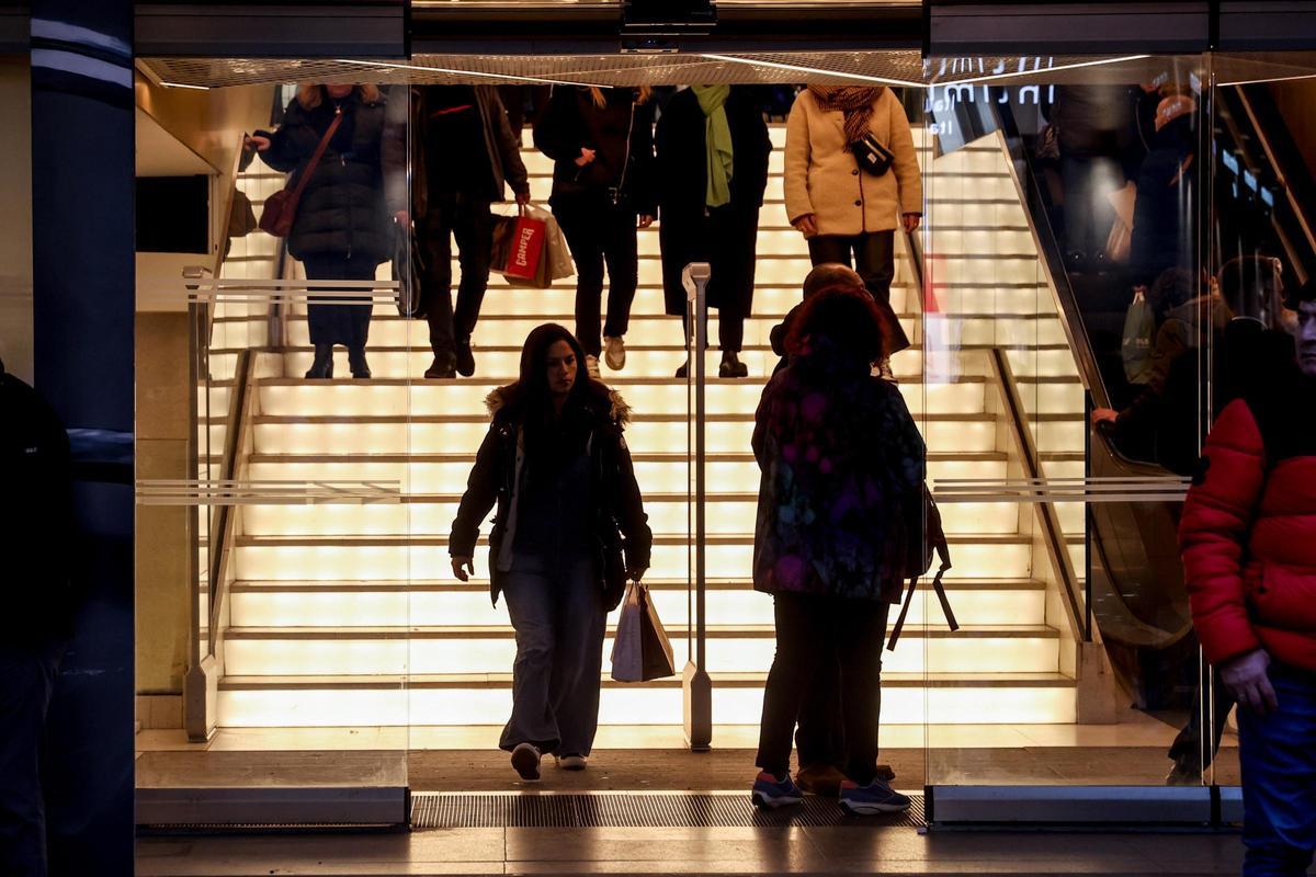 Varias personas entran y salen de un establecimiento comercial.