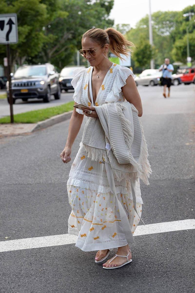 Jennifer Lopez con vestido blanco con bordados amarillos y sandalias planas