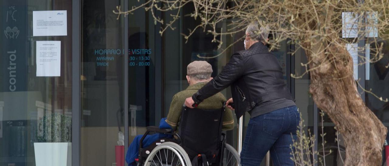 Una mujer, con un anciano en silla de ruedas.