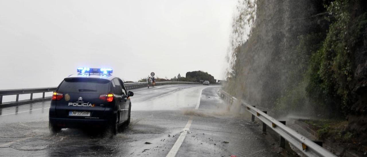 Un coche policial junto a la cascada que se forma en la carretera del Este cuando hay lluvias