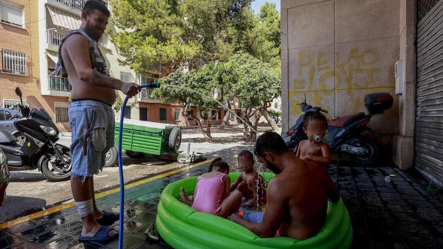 Varios niños de un barrio empobrecido junto a dos adultos durante una ola de calor este verano en València.
