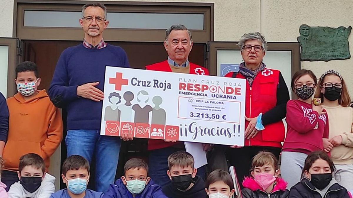 El director del colegio castropolense La Paloma, José Manuel Fernández, ayer, entregando el cheque a Ovidio Vila y Teresa Dorado, de Cruz Roja, en compañía de un grupo de alumnos. | R. T. C.