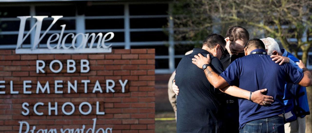 Quatre home preguen a l’entrada de l’escola on es va produir la massacre