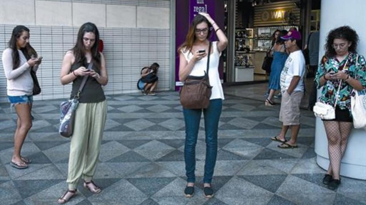 Cuatro ciudadanas consultan sus 'smartphones' en la plaza de Catalunya, en Barcelona.