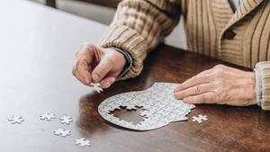 Un anciano hace un puzzle.