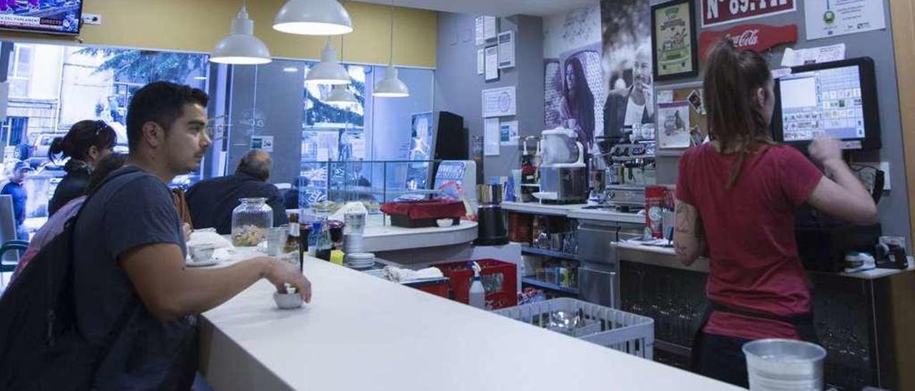 Estela Domínguez, en la caja de la cafetería Independencia, en Oviedo, con varios clientes ante la barra.