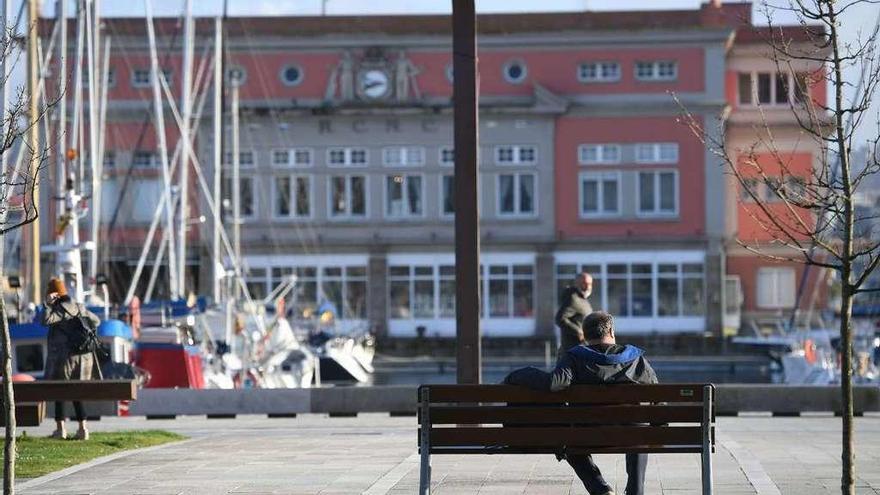 Un hombre disfruta del sol sentado en un banco de la Marina, en A Coruña.