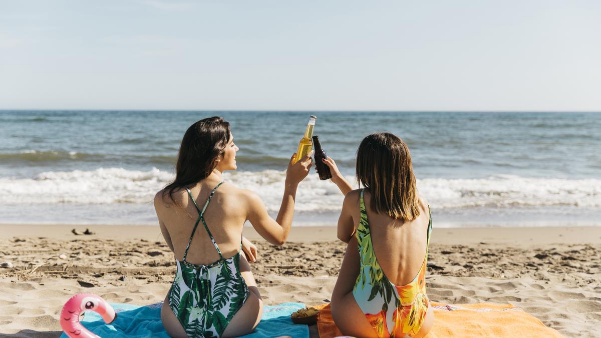 Dos mujeres brindando con cerveza en la playa