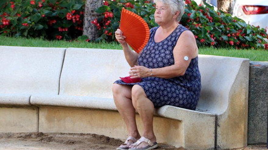 Una dona fent-se vent amb un ventall en una plaça de Figueres