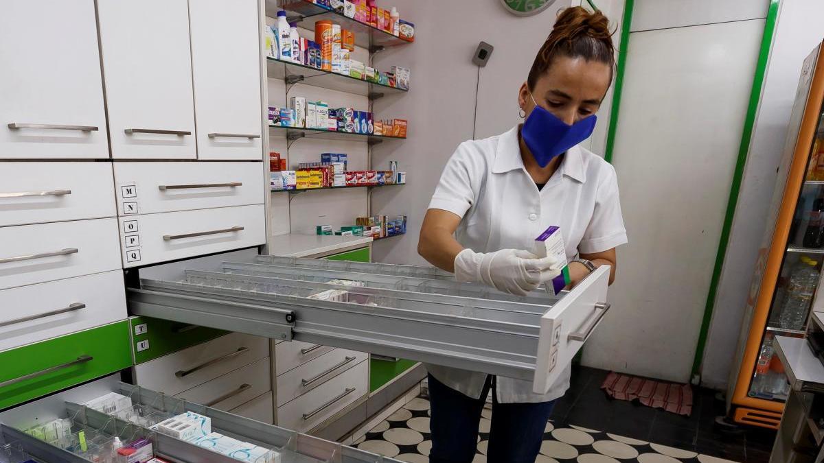 Una empleada busca medicamentos en un farmacia.