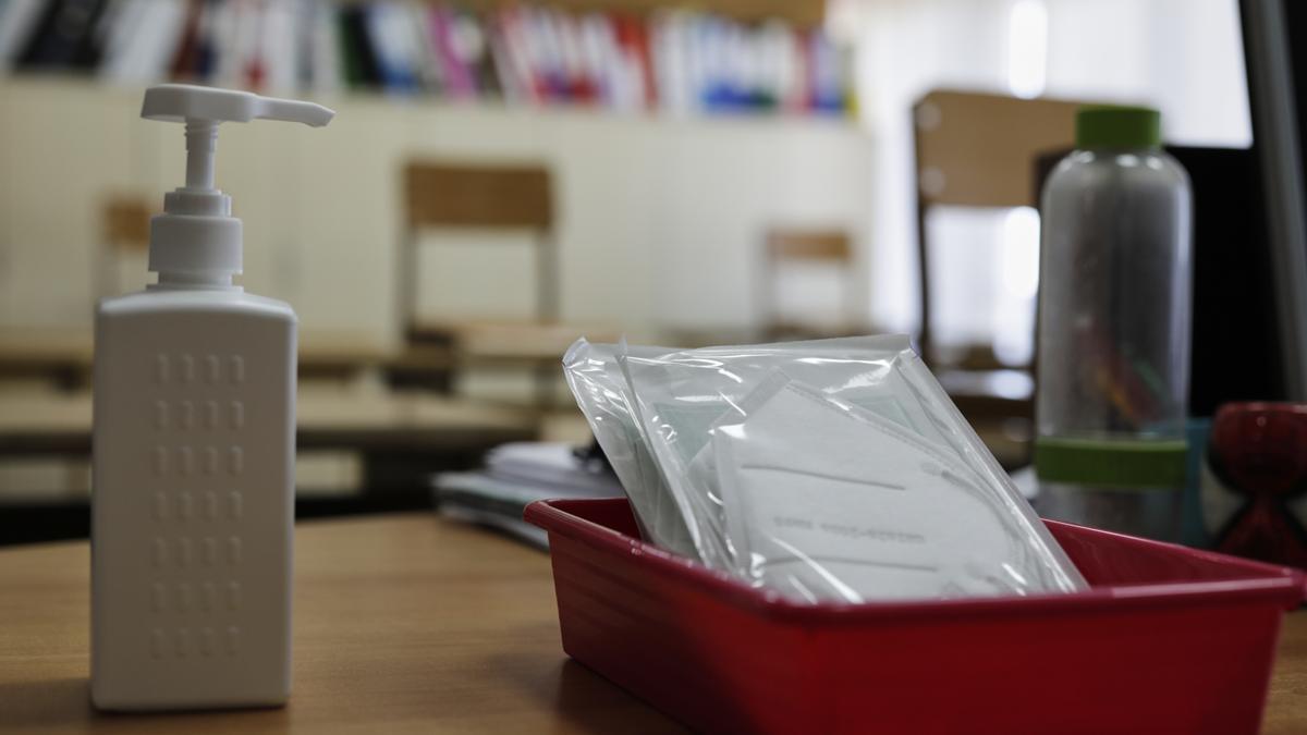 Mascarillas y gel desinfectante en la mesa del profesor de un aula.