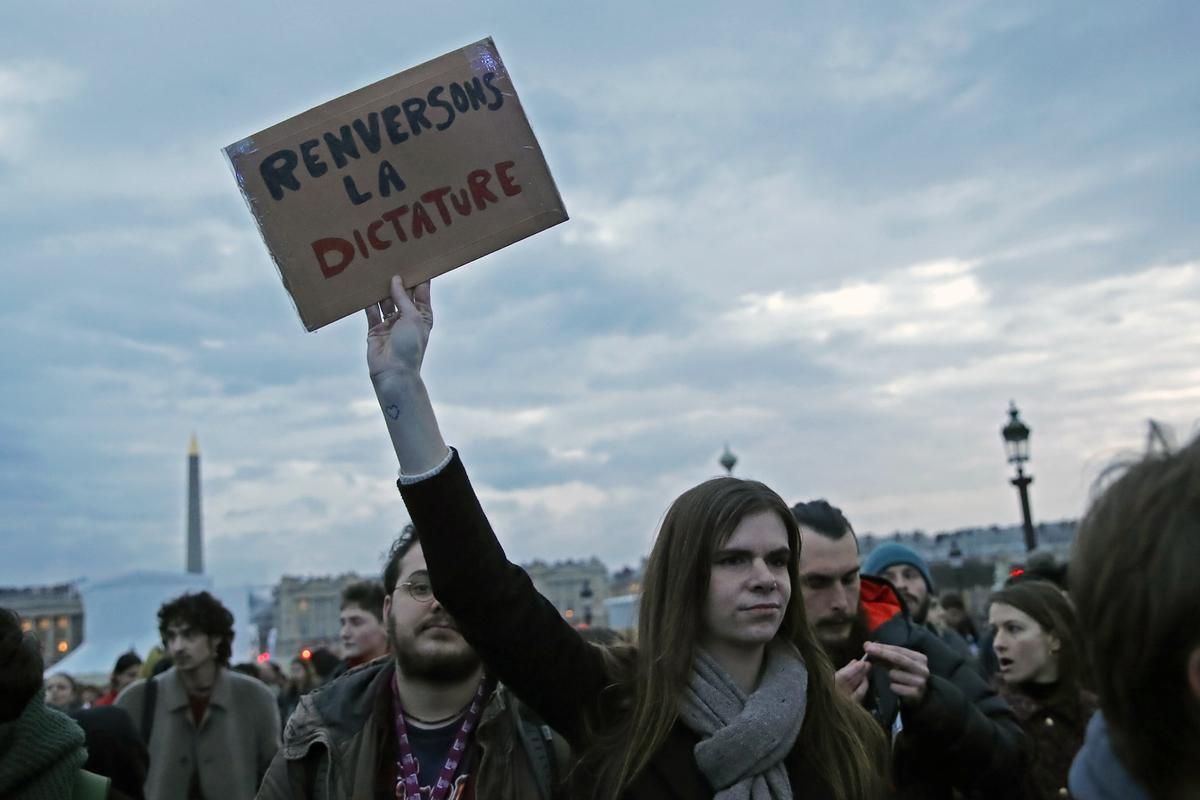 Paris (France), 17/03/2023.- A protester holds a placard reading ’Äòoverthrow the dictatorship’Äô as people gather at Concorde square near the National Assembly to protest against the pension reform law in Paris, France, 17 March 2023. Protests continue for the second day near the National Assembly after French Prime Minister Elisabeth Borne on 16 March had announced the use of article 49 paragraph 3 (49.3) of the Constitution of France to have the text on the controversial pension reform law to be definitively adopted without a vote. (Protestas, Francia, Concordia) EFE/EPA/TERESA SUAREZ