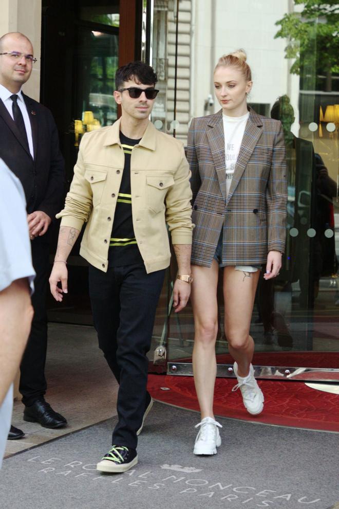 Sophie Turner con blazer a cuadros y shorts, junto a Joe Jonas