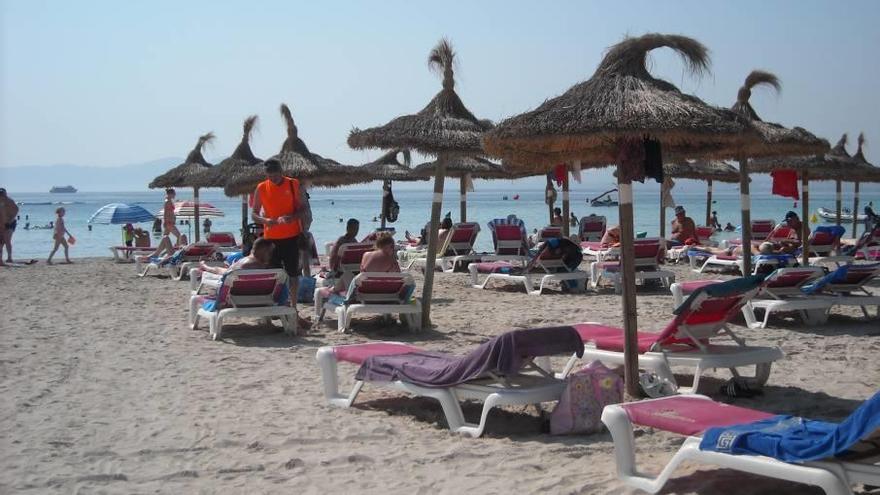 Un trabajador cobra las hamacas en la playa del puerto de Alcúdia en un pasado verano.