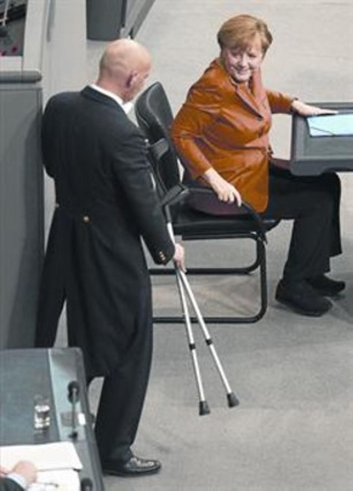 Un uixer porta les crosses a Merkel després del seu discurs al Bundestag. Un uixer porta les crosses a Merkel després del seu discurs al Bundestag.