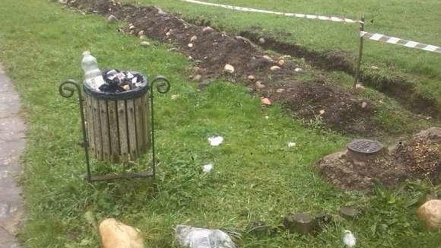 Detalle de una papelera llena y con basura en el suelo en el área recreativa de La Isla, en Blimea.