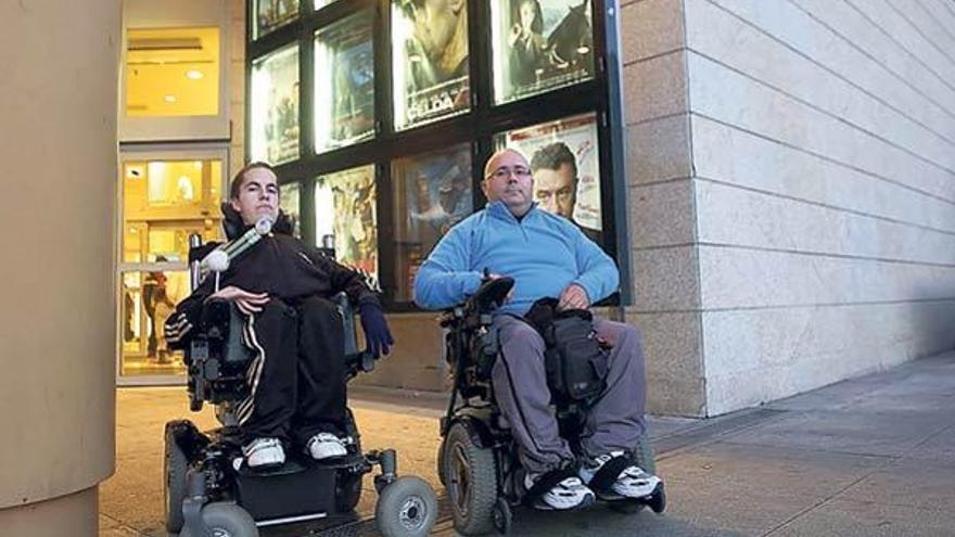 Dos jóvenes de la asociación Apamp de Vigo frente a la cartelera de este fin de semana.  // J. Lores