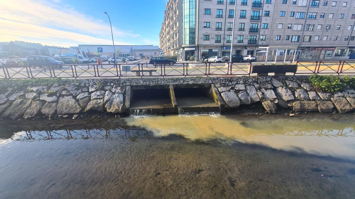 El vertido que este Jueves Santo salía al río Con desde el regato canalizado que pasa bajo Fexdega, al fondo.