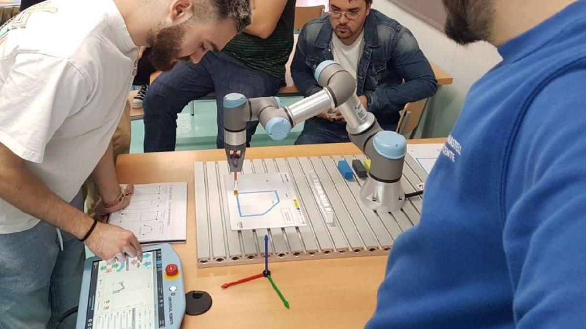Alumnos trabajan con un cobot o brazo robótico