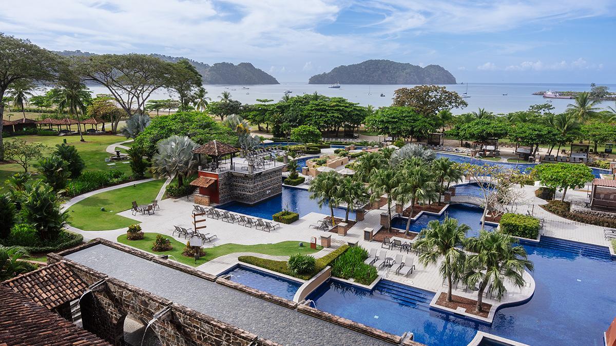 Vista de las piscinas y los jardines tropicales de Los Sueños Marriott Ocean &amp; Golf Resort, frente al Pacífico costarricense y rodeado de exuberante vegetación.
