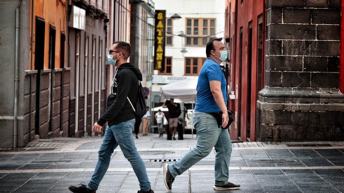 Dos personas pasean en Santa Cruz de Tenerife con mascarilla en una imagen de archivo.