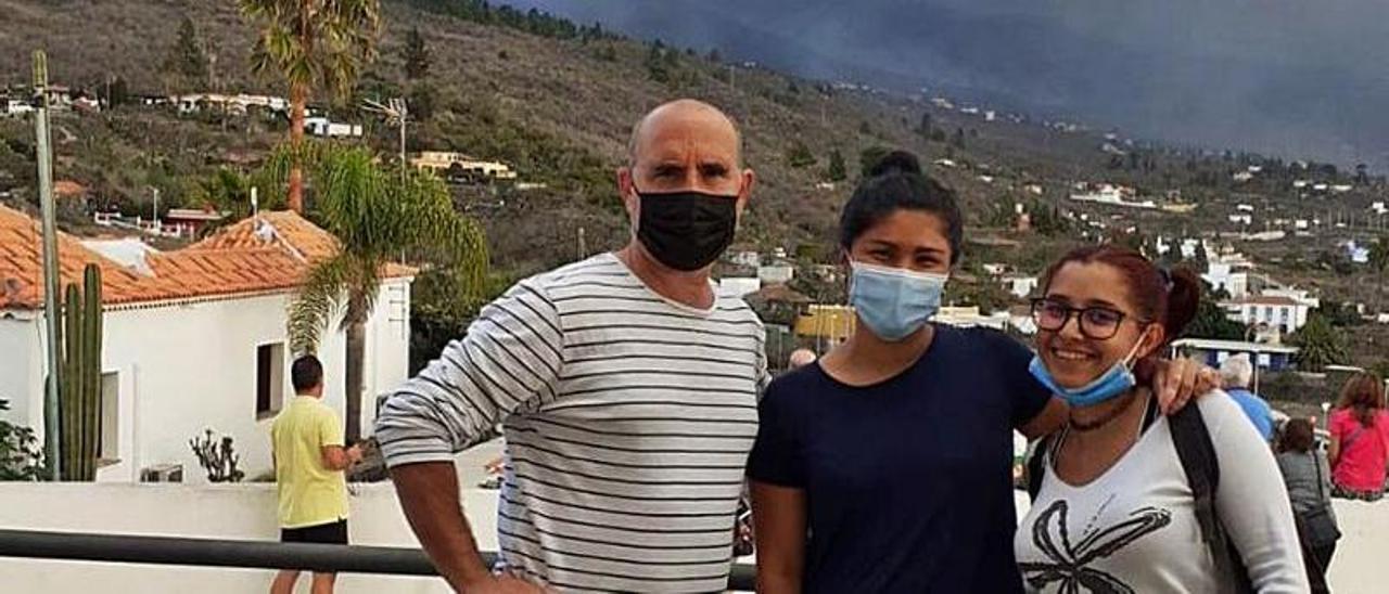 Pablo Jiménez, con dos alumnas de su escuela de hostelería, ayer en la iglesia de Tajuya, situada a dos kilómetros del volcán (al fondo). | LNE