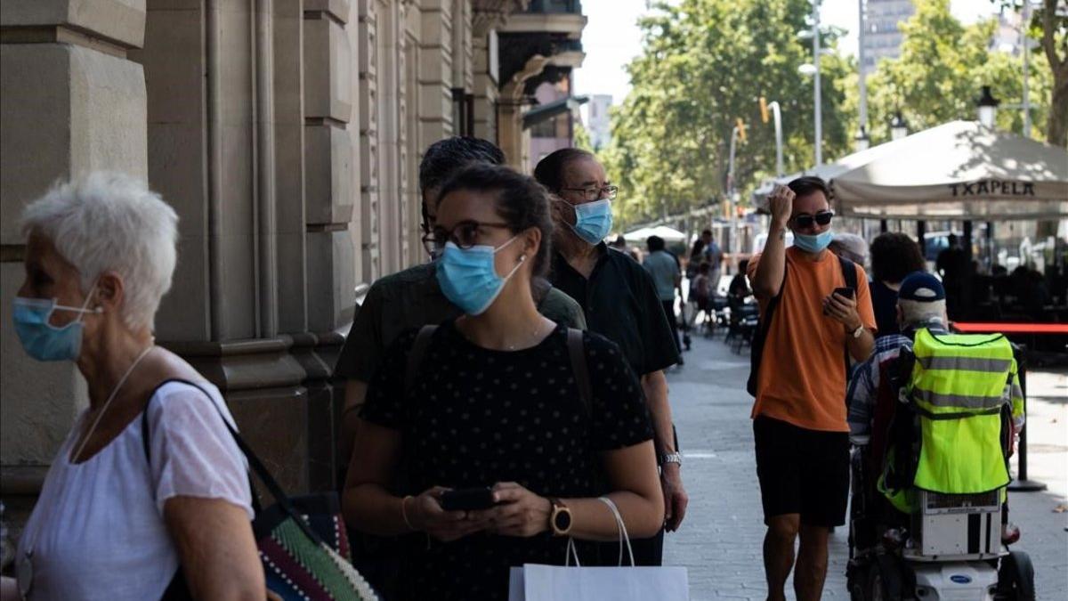 Gente con mascarilla en el paseo de Gràcia de Barcelona