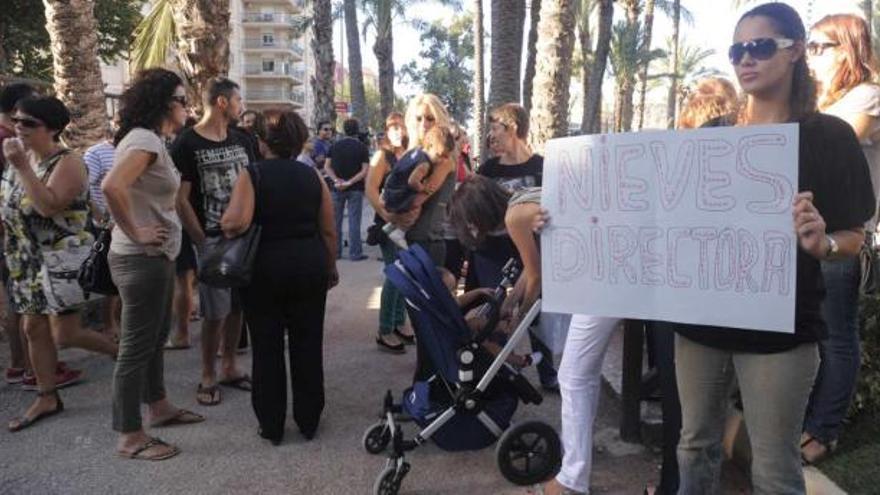 Un grupo de padres y madres protestan delante de la entrada de la escuela.