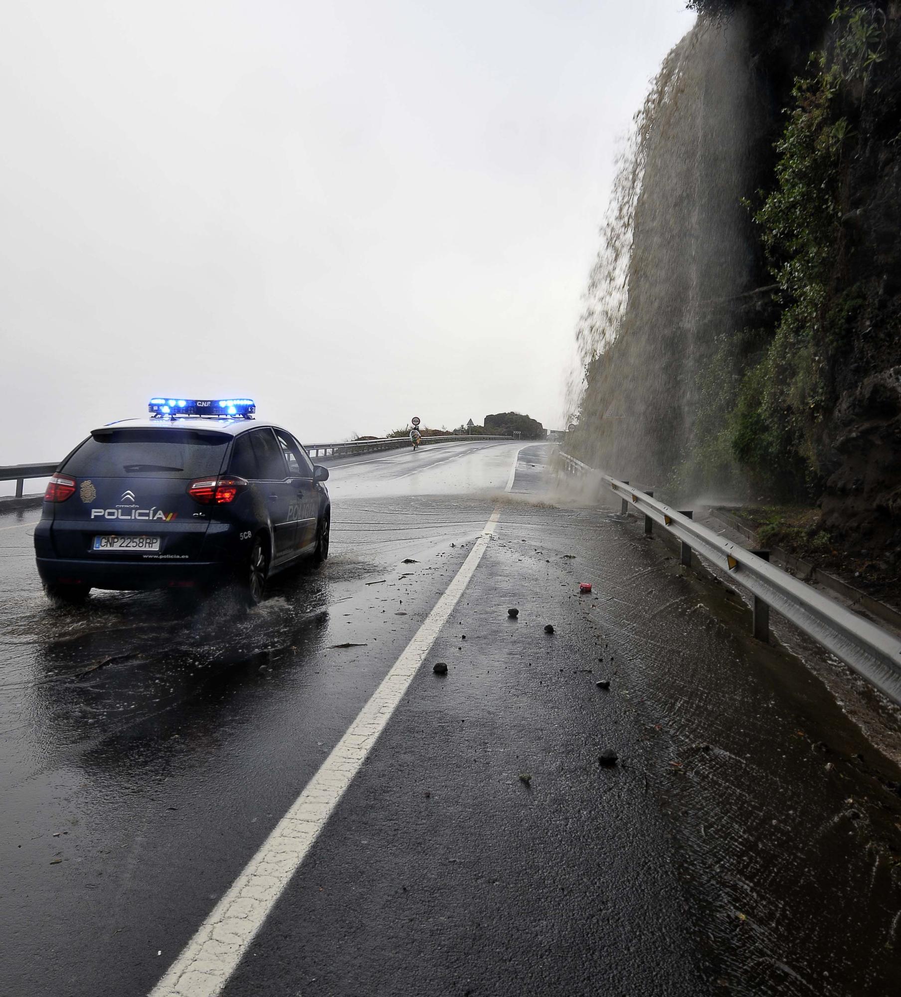 Un coche policial junto a la cascada que se forma en la carretera del Este cuando hay lluvias