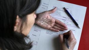 Una chica estudia matemáticas con una chuleta de fórmulas en su mano.