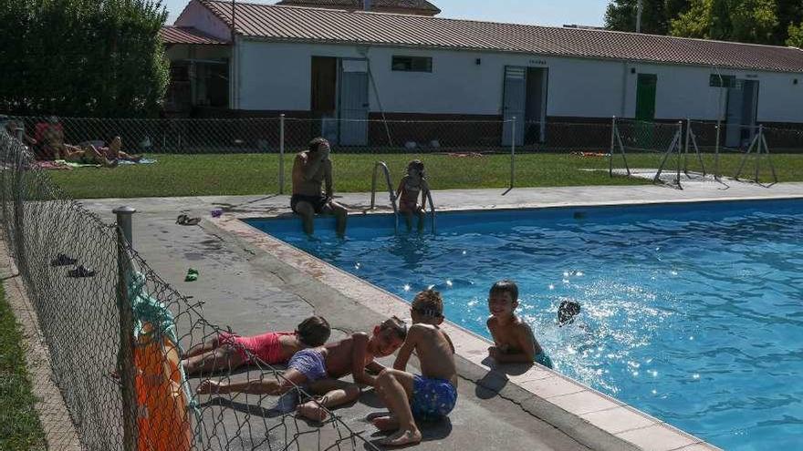 Varios niños juegan en el borde de la piscina del barrio de Pinilla.