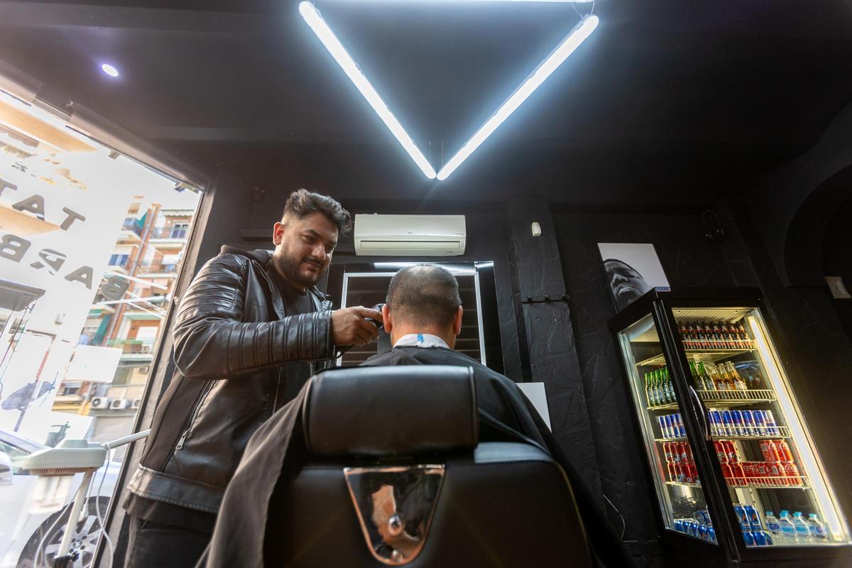 Thiago Santana corta el pelo a un cliente en su peluquería.
