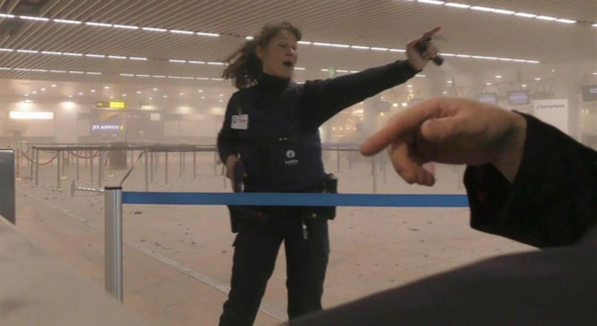 La policía dirige a los pasajeros por la terminal llena de humo del aeropuerto de Bruselas.
