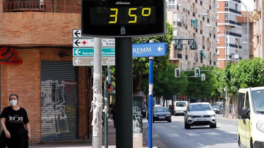 Una mujer pasa junto a un termómetro que marca 35 grados en Murcia.