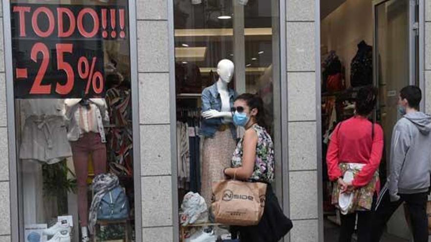 Una mujer pasea ante el escaparate de una tienda de la calle Real.