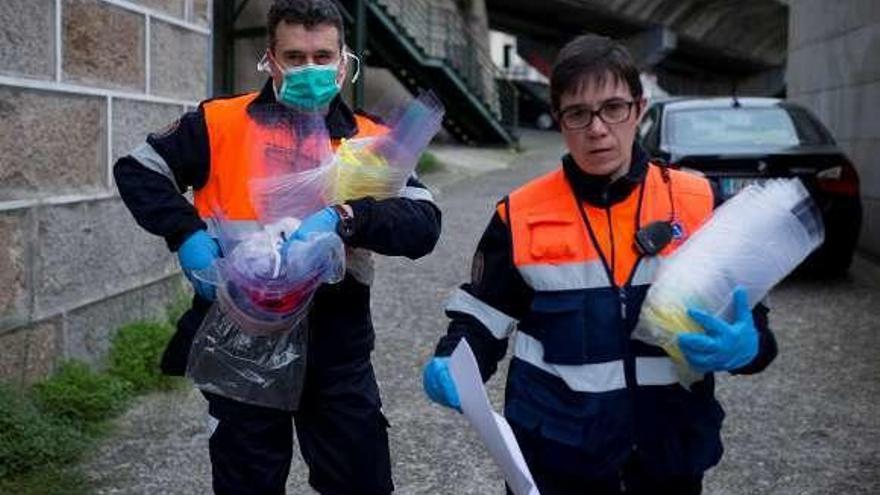 Dos voluntarios de Protección Civil transportan viseras . // Efe / B. L.