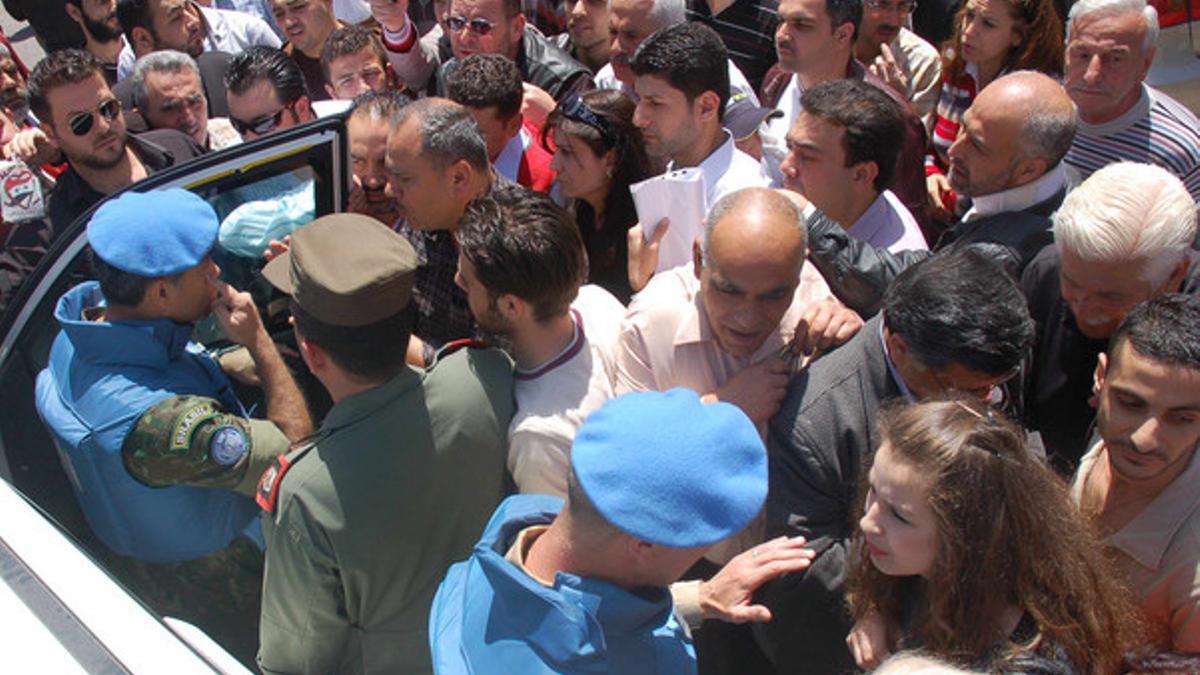 Observadores de la ONU, acompañados por soldados del régimen, hablar con civiles sirios, el lunes en la ciudad de Homs.