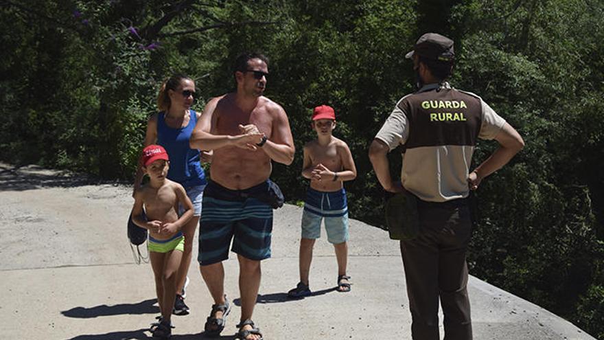 Un vigilant conversa amb turistes en una zona propera a la riera