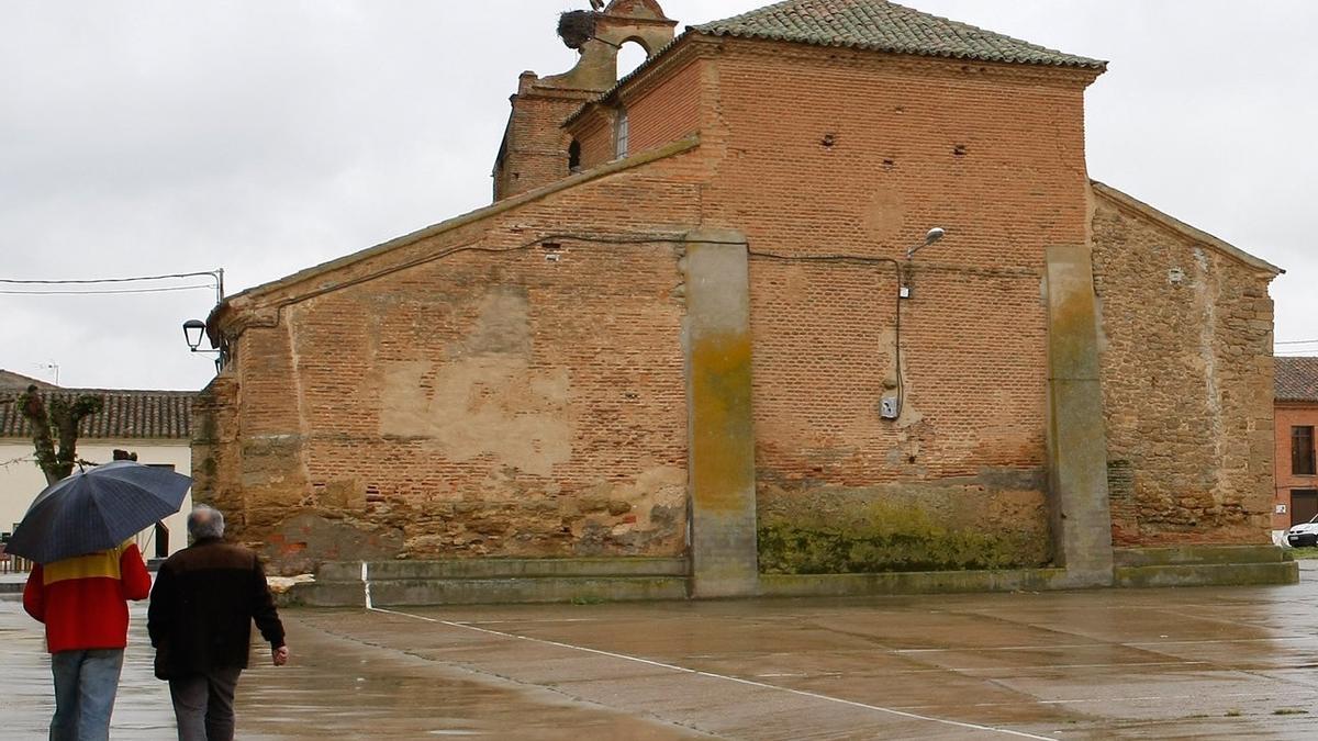 Vecinos pasean por el entorno de la iglesia de Revellinos de Campos