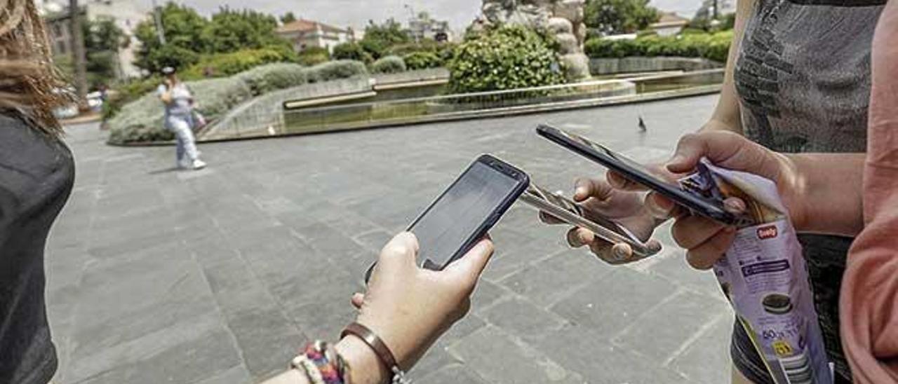 Un grupo de jóvenes consulta el móvil en la plaza de España de Palma.