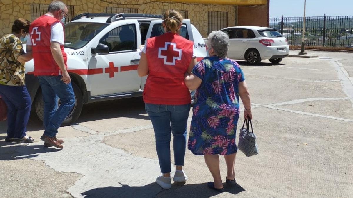 Voluntarios de Cruz Roja acompañando a votar a dos mujeres de la tercera edad.