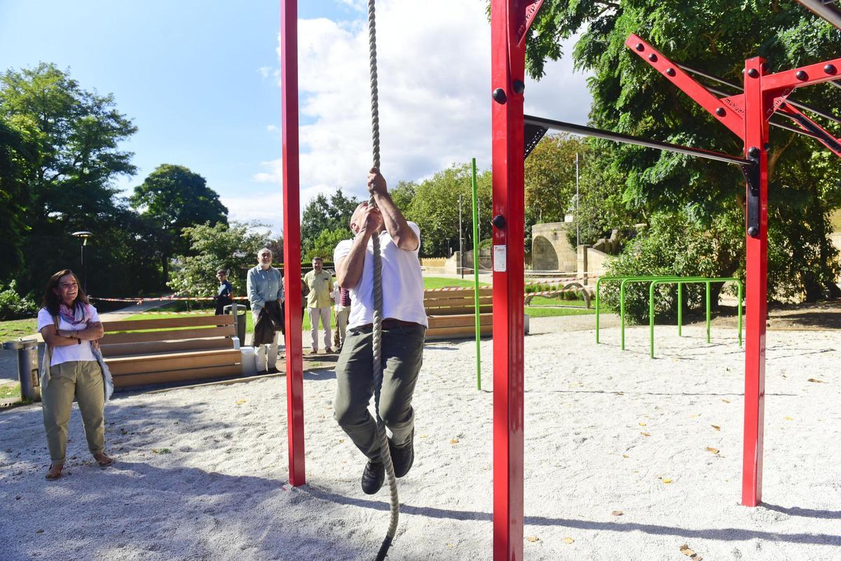 El concejal Chero Celemín trepa por una cuerda de una nueva zona de calistenia en el parque de Santa Margarita, con la alcaldesa Inés Rey a la izquierda