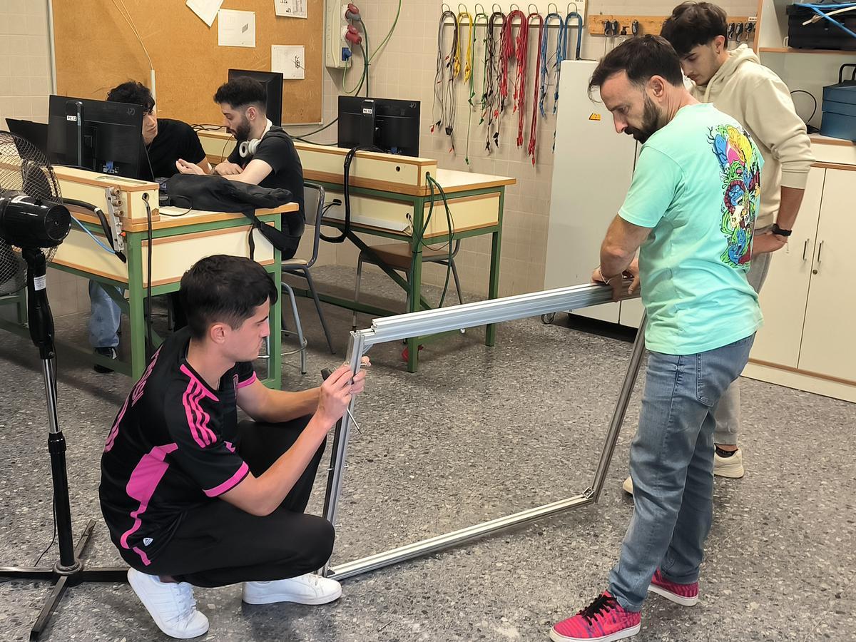 Alumnat del Grau Superior de Disseny en Fabricació Mecànica de l’IES Gonzalo Anaya de Xirivella junt amb el seu professor, Joaquín Sánchez, embastant el marc del prototip de comporta antiinundacions que han creat.