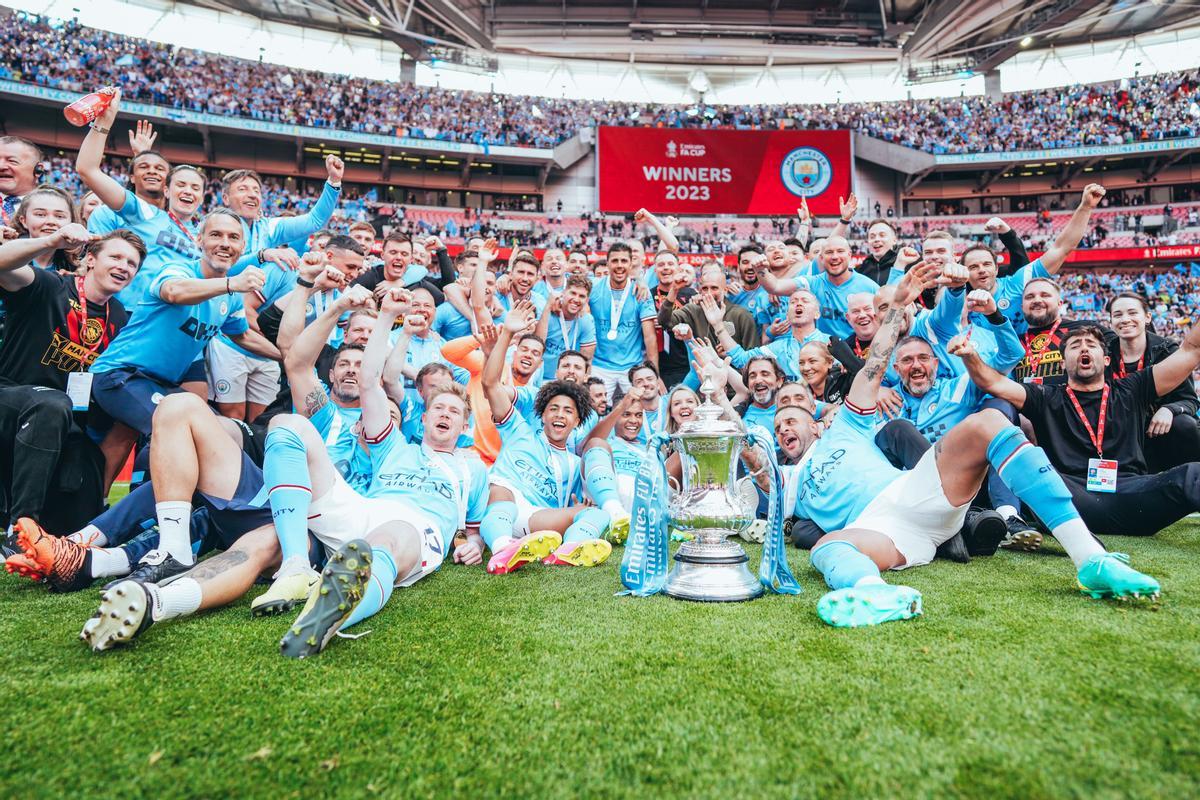 mancester City celebra la Champions League. Carlos Vicens (a la izquierda, con pantalón azul y la camiseta del City) posa junto a la plantilla del equipo inglés