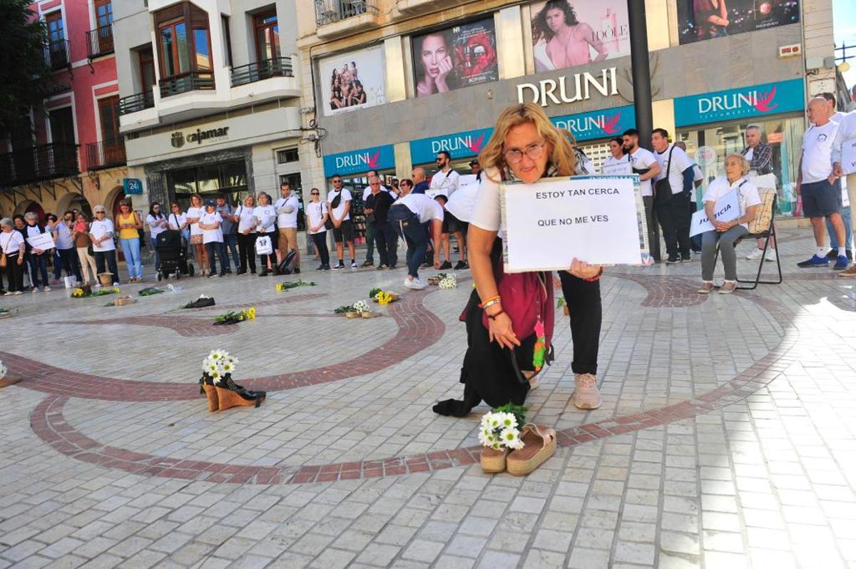 Una de las usuarias de Cáritas Elche con un cartel pidiendo más visibilidad hacia las personas sin techo