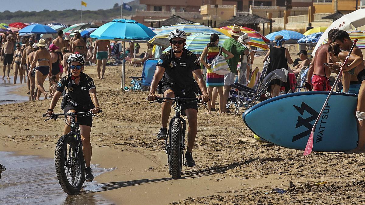 Dos agentes realizan labores de vigilancia al borde de la orilla en sus bicicletas, en la playa de Arenales del Sol, en una imagen reciente. | ANTONIO AMORÓS