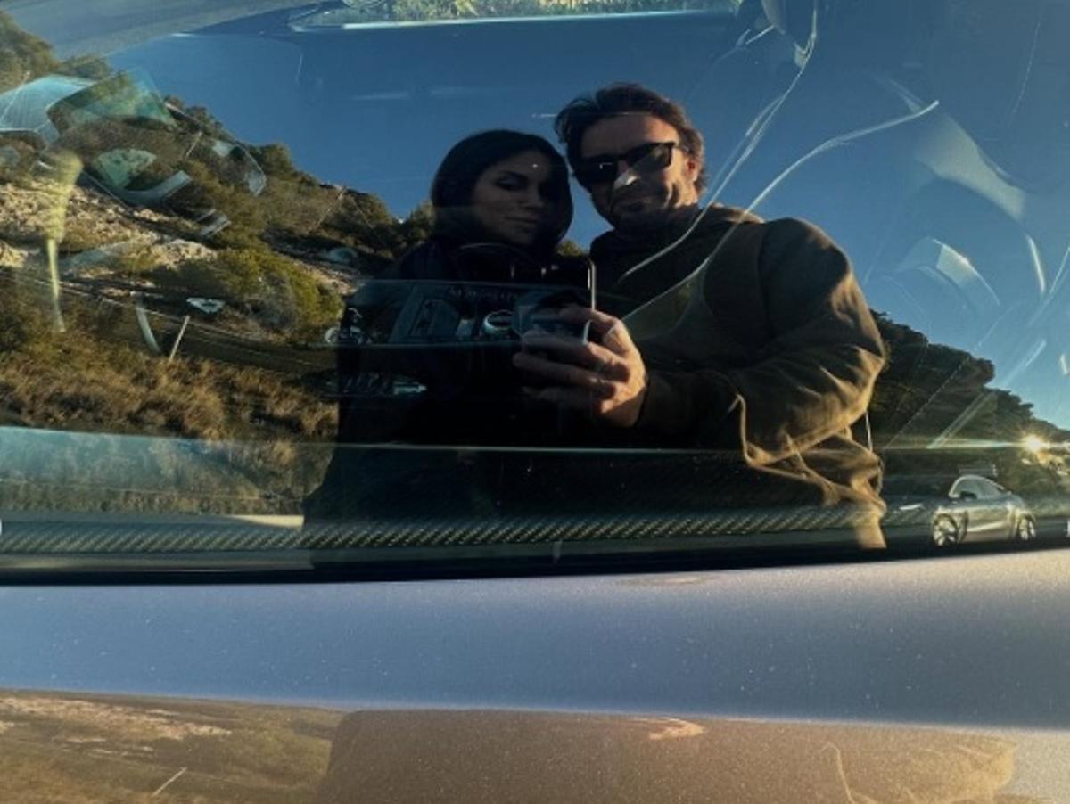 Melissa Jiménez y Fernando Alonso reflejados en el cristal de su deportivo