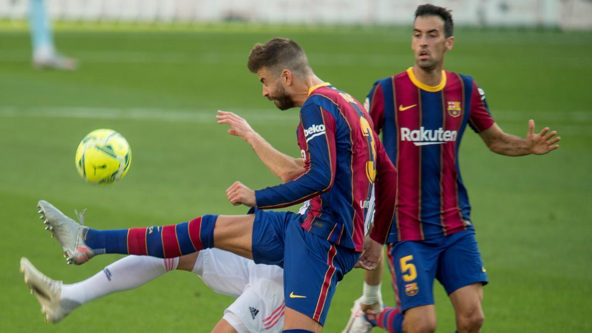 Piqué y Benzema pugnan por un balón en presencia de Busquets.