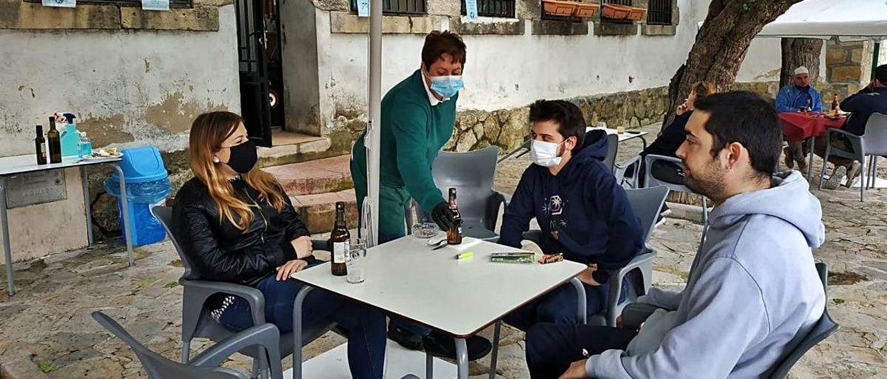 Tres jóvenes comparten mesa en la terraza del único bar de Benilloba que ha abierto, el pasado viernes.