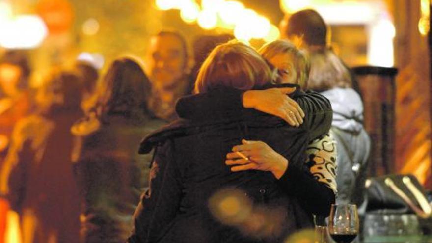 Dos mujeres se funden en un abrazo a las puertas de una vinatería de Mieres el viernes por la noche.